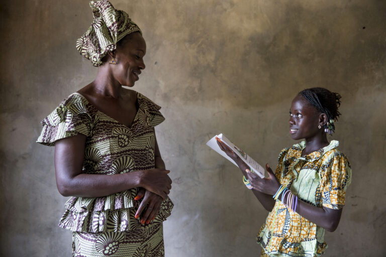 KEUR ALPHA, SENEGAL - AUGUST 12: A child reading to her mother in their local Wolof language. The children's books in the local language was developed and printed by TOSTAN to help preserve the local languages in rural areas in Senegal. The program is part of TOSTAN's Reinforcement of Parental Practices Module, where by applying the knowledge gained during the Reinforcement of Parental Practices Module, parents and community members will give children an excellent start in their social, linguistic, and emotional growth. This healthy development will in turn lead to more children staying in and excelling in school, and improve child parent relationship. August 12, 2014 in Keur Alpha, Senegal. (Photo by Jonathan Torgovnik/Reportage by Getty Images)..